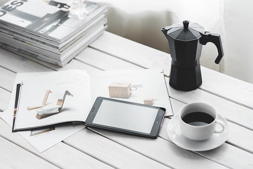 Une table avec une tablette, du café et des magazines