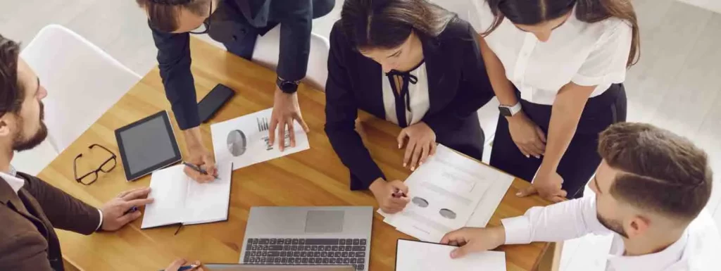 Plusieurs personnes travaillent sur un bureau de couleur marron