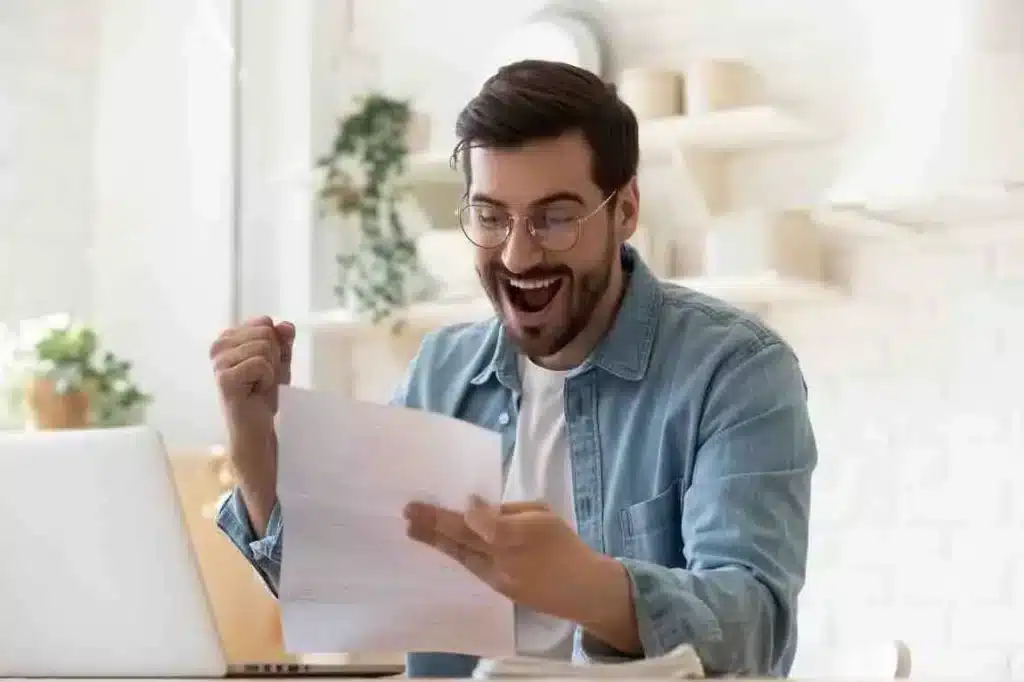 Un homme lit une bonne nouvelle sur un papier, il est heureux
