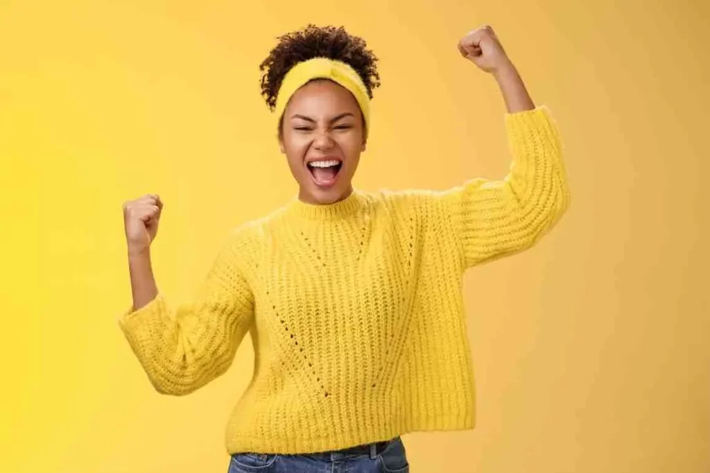 Une personne habillée avec un pull jaune est heureuse