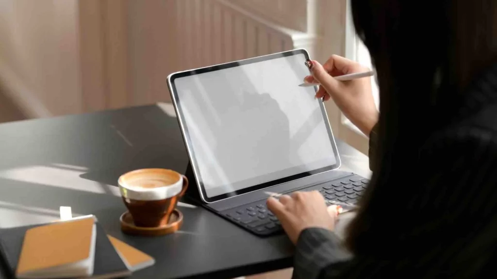 Une personne qui est son propre patron travaille sur sa tablette avec un café