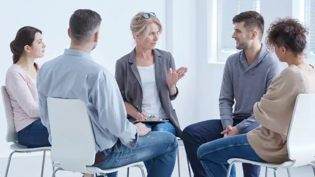 Une médiatrice discute avec un groupe de personne pour gérer un conflit ou une situation au travail