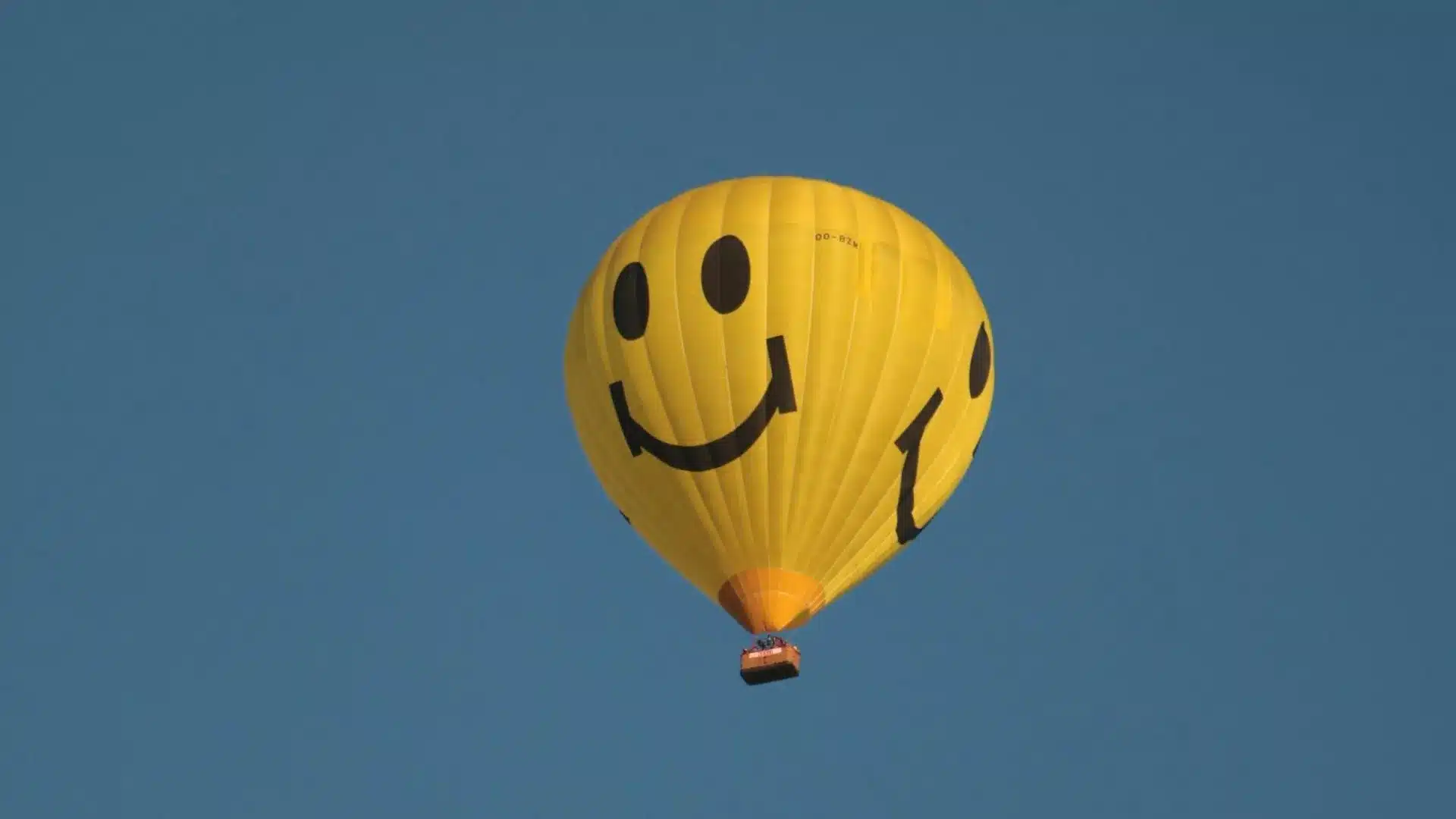 Une montgolfière jaune avec smiley dans le ciel bleu