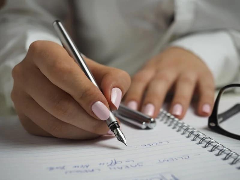 Une femme qui communique à l'écrit sur un cahier.