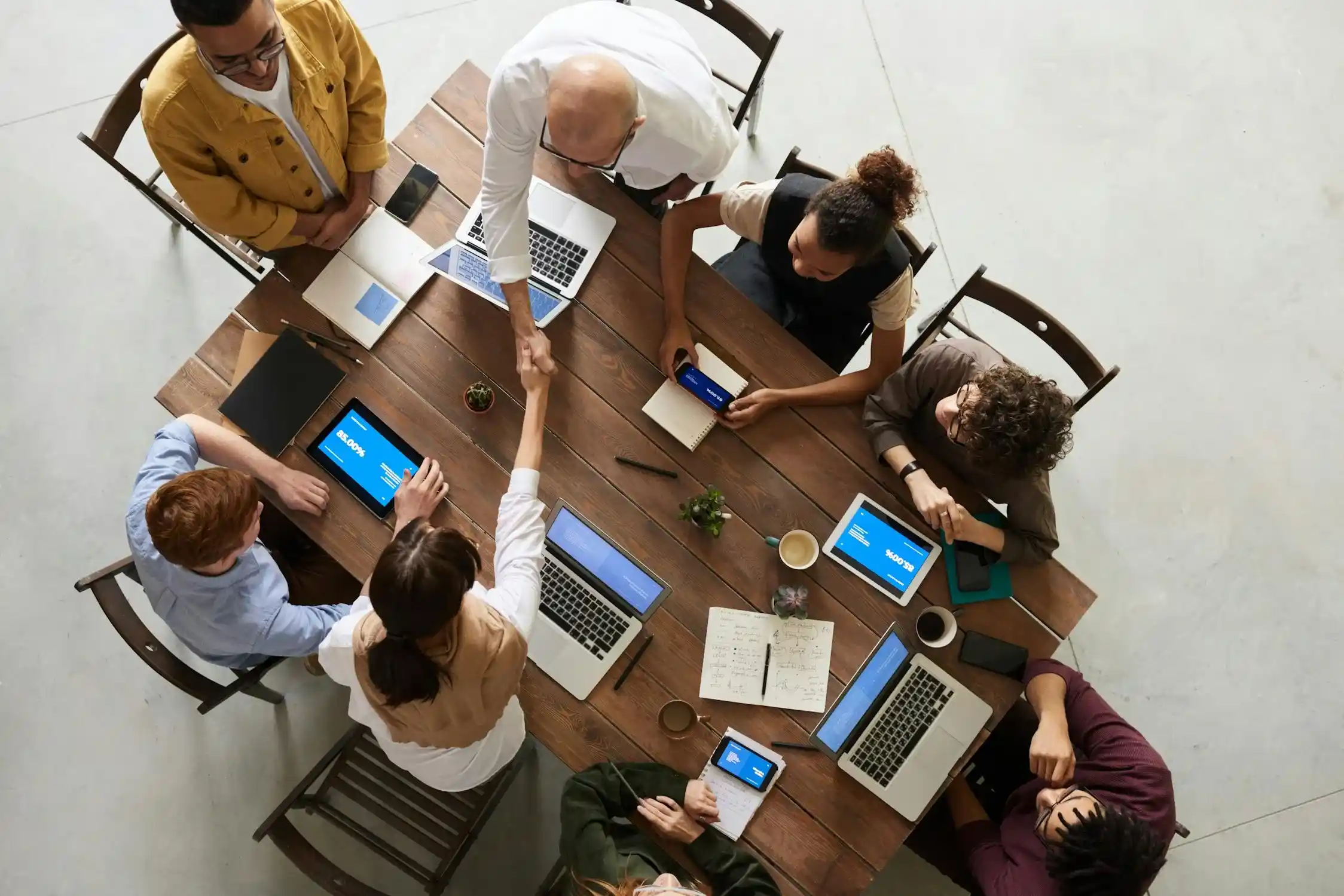 Plusieurs personnes travaillent ensemble autour d'une table avec leurs ordinateurs.