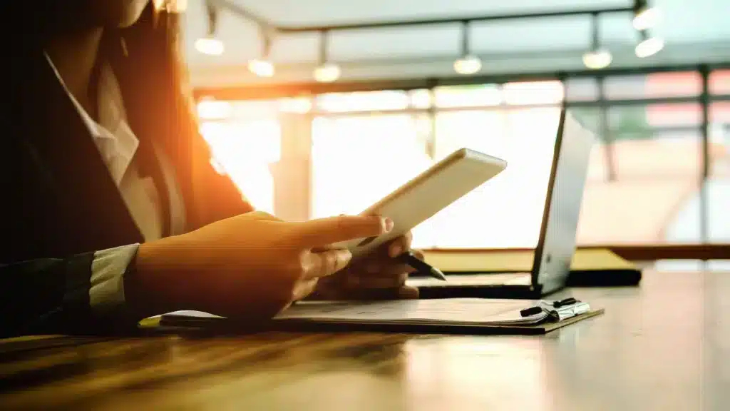 Une femme en costume est à son bureau en train de manipuler une tablette