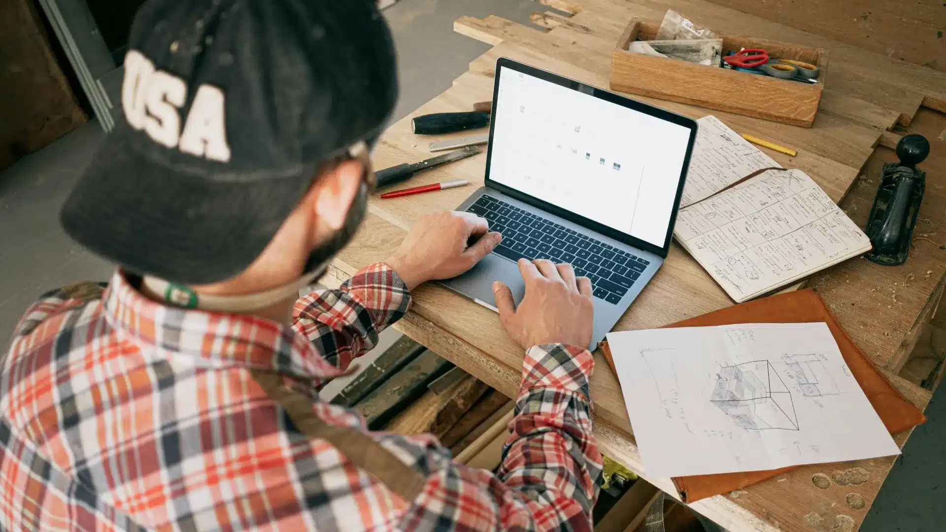 Un homme, artisan, travaille sur son ordinateur dans son atelier pour améliorer sa stratégie commerciale 