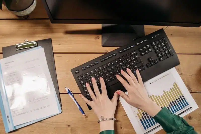 Une femme écrit sur son clavier est en train de réaliser un bilan de compétences.