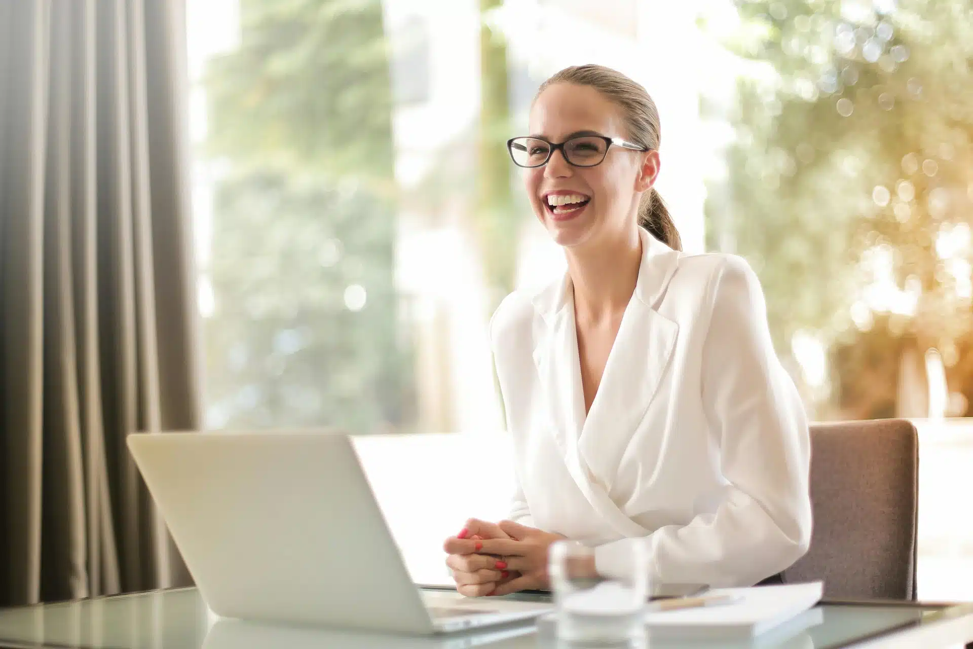 Une femme qui souriante à son bureau.