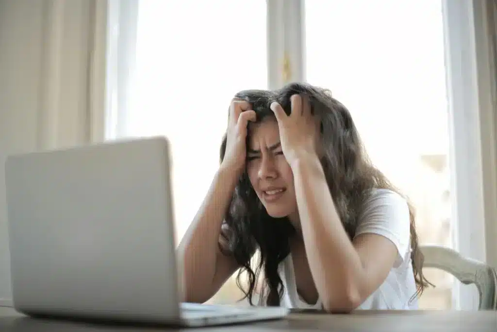 Une jeune femme à bout devant son ordinateur au travail.