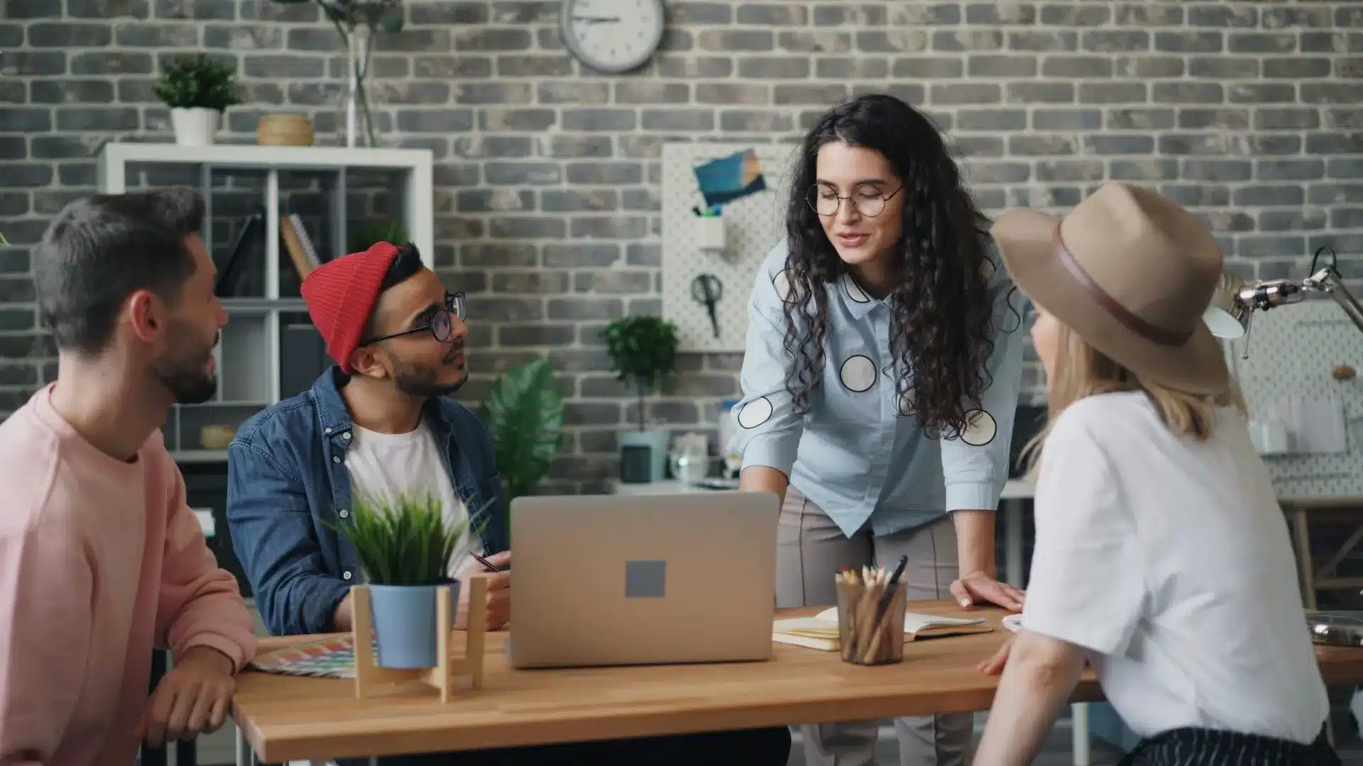 Une équipe discute dans un bureau. Il y a 4 personnes autour d'un bureau et d'un ordinateur