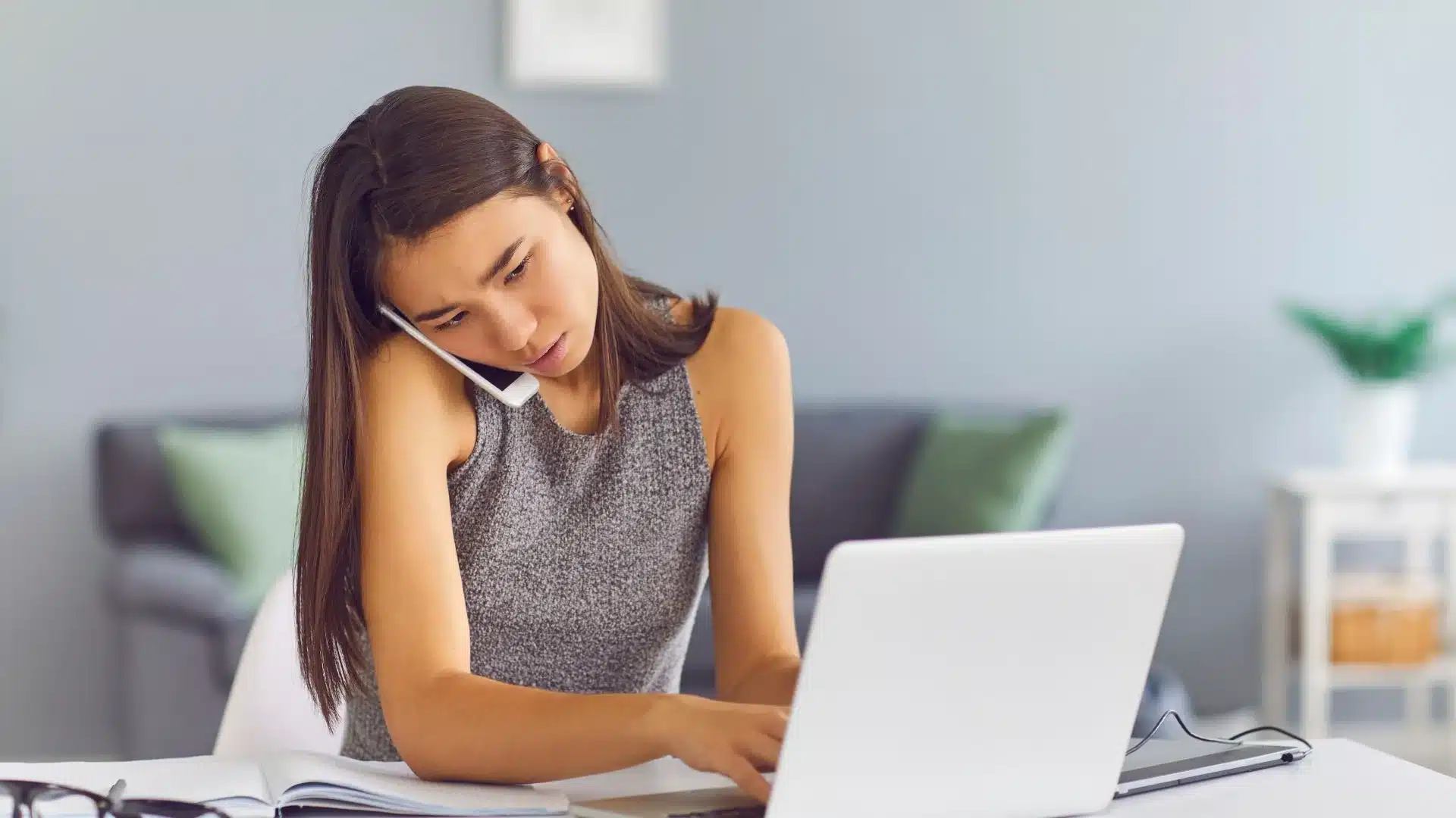 Un community manager est sur son ordinateur et en même temps au téléphone.